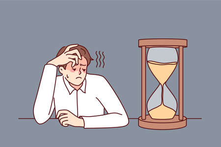 Tired businessman looking at hourglass