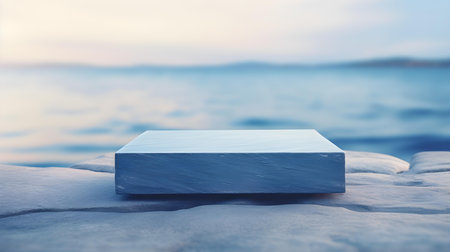 Square Stone Podium in blue Colors in front of a blurred Seascape. Luxury backdrop for product presentationの素材