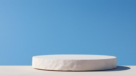 Round stone podium in front of a blue studio background. White Pedestal for Product Presentationの素材