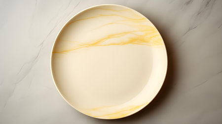 Top view of an empty plate in light yellow colors on a white marble background. Elegant template with copy spaceの素材