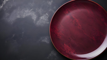 Top view of an empty plate in red colors on a black marble background. Elegant template with copy spaceの素材