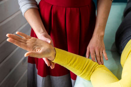 Close-up of a female physiotherapist holding hands of a young woman.の写真素材