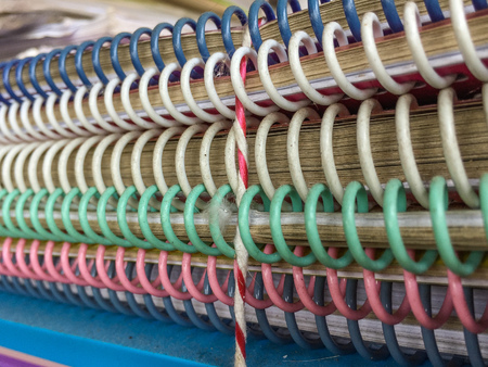Stack of dirty used spiral bound notebook. Plastic spiral bound colors is blue, white, green and pink.の写真素材