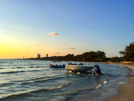 Two peoples trolleying the boat into the sea on the evening.の写真素材