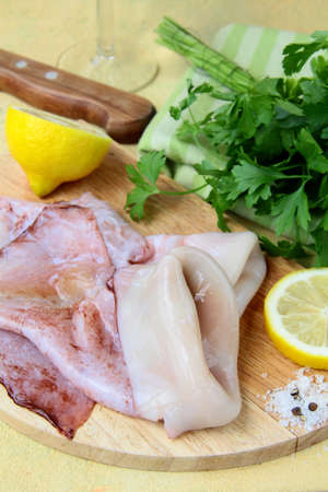 fresh raw squid on a kitchen board with herbs and lemonの写真素材