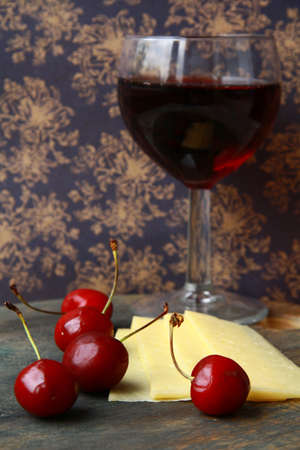 glass of red wine, cheese and cherry - a still life in vintage styleの写真素材