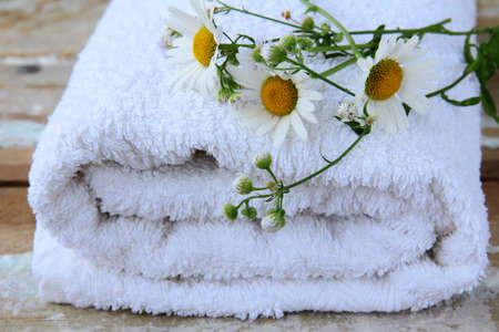 white towel with daisies on a wooden tableの写真素材