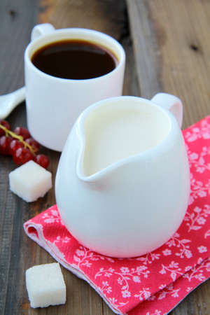 white jug with milk and coffee on wooden backgroundの写真素材
