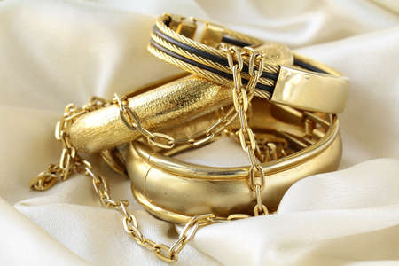 gold jewelry, bracelets and chains on silk 
