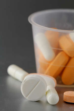 plastic cup with pills on a gray  background