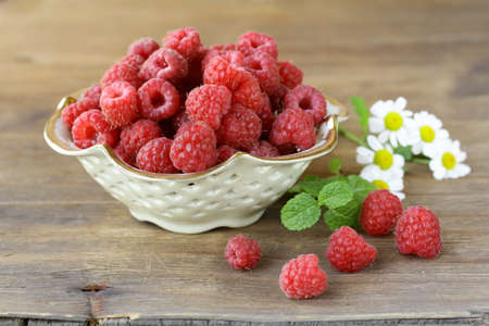 juicy ripe raspberries with mint leaves in a cup
