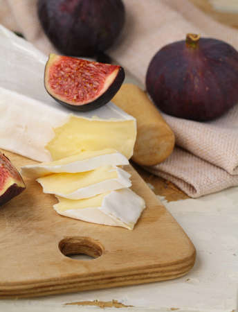 Brie cheese and sweet fruit  figs on a wooden boardの写真素材