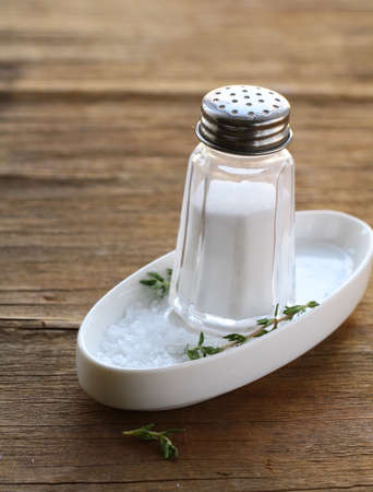 Glass saltcellar with salt on wooden tableの写真素材