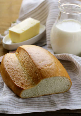 butter,  loaf of white bread and milk on wooden plateの写真素材