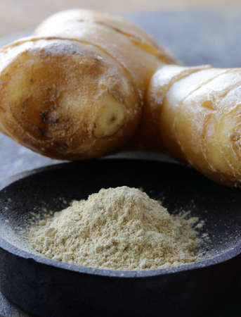ground ginger (spice) and fresh on a wooden board