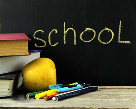 stationery  pen, pencil, ruler, compass  and a book on black school board backgroundの写真素材