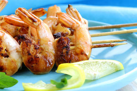 shrimp grilled on wooden skewers with lemon and basilの写真素材