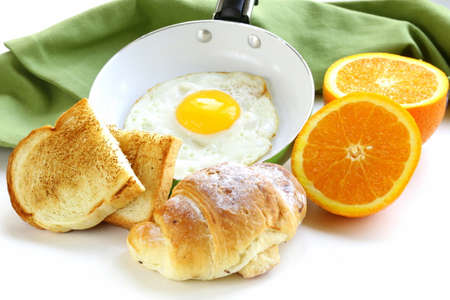 Continental breakfast - croissant, fried egg, toast and orangesの写真素材