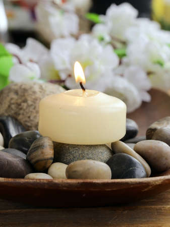 still life a lit candle and stones on wooden backgroundの写真素材