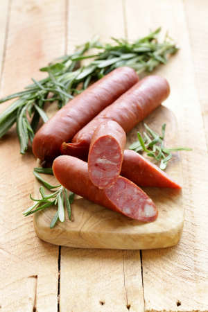 Dried sausage with  fresh rosemary on a wooden background