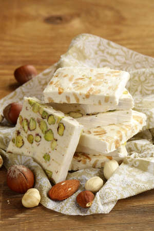 white nougat with different nuts on a wooden table