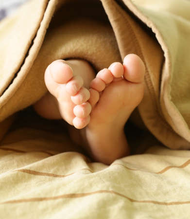 little baby feet under a warm blanket  in beige color の写真素材