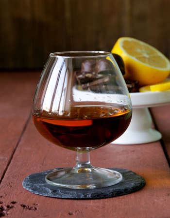 glass of brandy with chocolate on wooden tableの写真素材