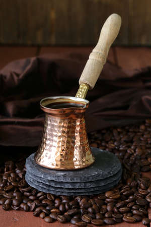 copper coffee pot with beans on a wooden tableの写真素材