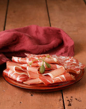 sliced dried sausage meat  ham, prosciutto, salami  served on a wooden board