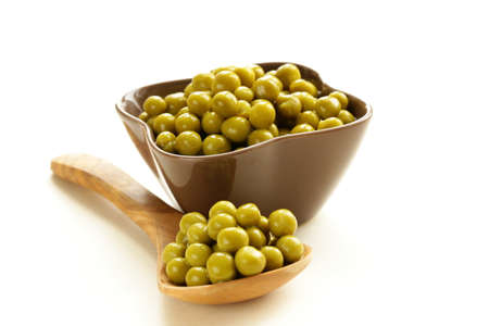 canned green peas in a wooden spoon macro shot