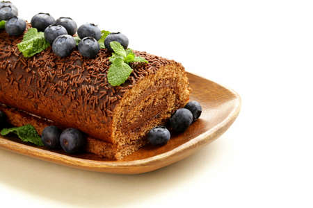 chocolate biscuit roll garnished with mint leaves and blueberriesの写真素材