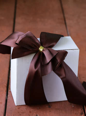 white gift box with ribbon bow on a wooden backgroundの写真素材