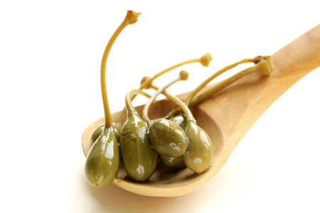 Pickled gourmet green capers in a wooden spoonの写真素材