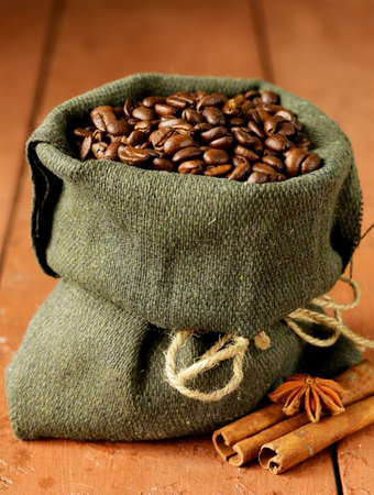 Still life of coffee beans in canvas sack on vintage wooden tableの写真素材