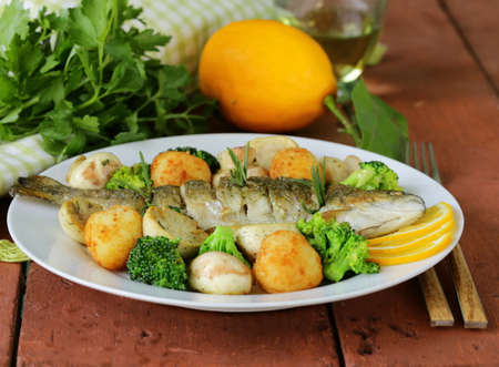 roasted trout fish with vegetables and lemon on a plateの写真素材