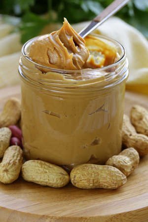 homemade peanut butter with whole nuts on a wooden tableの写真素材