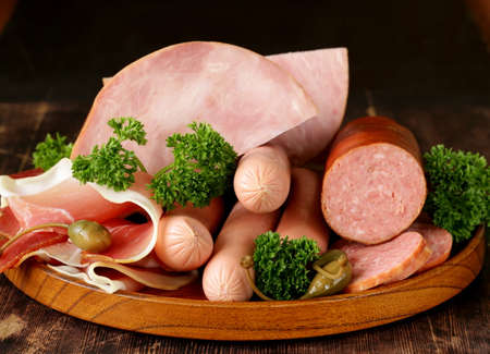 various kinds of sausages and smoked bacon on the wooden plate
