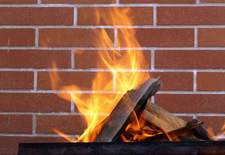 burning wood in a brazier on the brick wall backgroundの写真素材