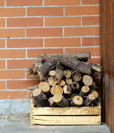 dry chopped firewood logs in a pile on the brick wall backgroundの写真素材