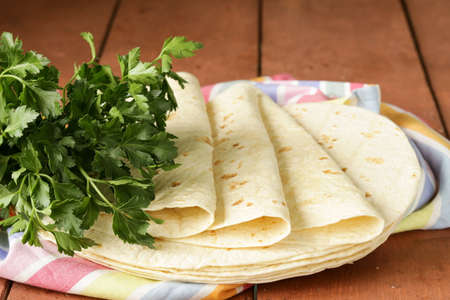 stack of homemade whole wheat flour tortillas on a wooden table