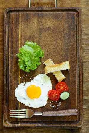fried egg with fresh vegetables and toast for breakfastの写真素材