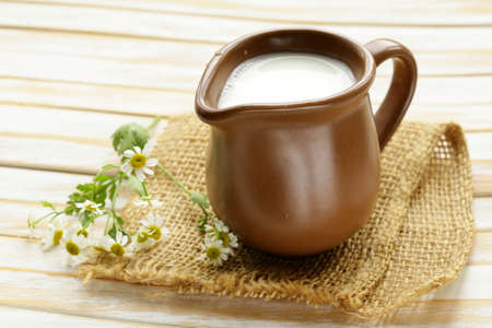 natural fresh milk in a ceramic jug on a wooden tableの写真素材