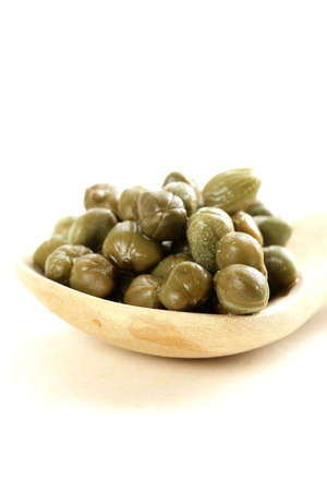 Pickled gourmet green capers in a wooden spoonの写真素材