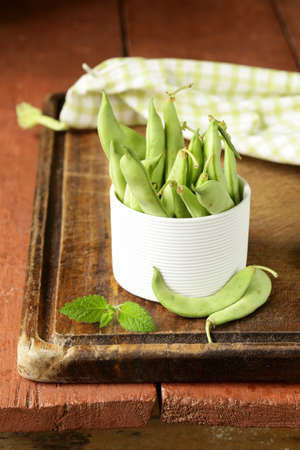 pods of green peas on a wooden table
