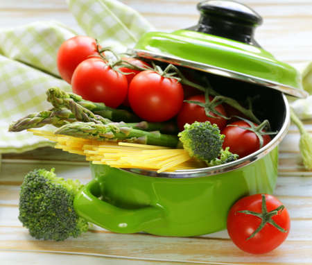 green pot full of vegetables  tomatoes, asparagus, mushrooms, broccoli  and pastaの写真素材