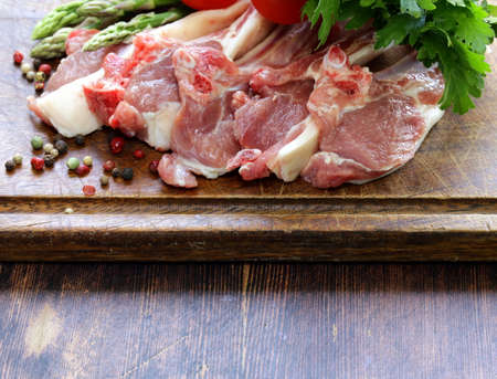 raw meat, lamb chops with vegetables on wooden board