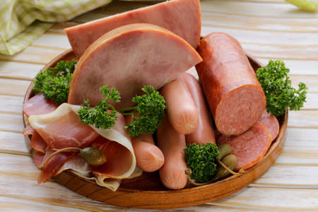 various kinds of sausages and smoked bacon on the wooden plateの写真素材