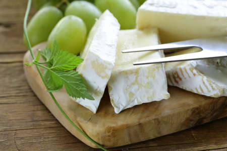 Soft brie cheese with sweet grapes on a wooden boardの写真素材