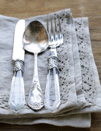 vintage silver cutlery with linen napkin on wooden backgroundの写真素材