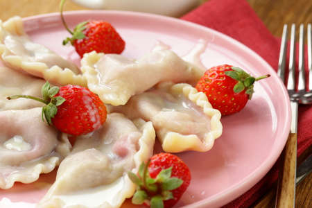 dumplings with berries and cream sauce served with fresh strawberriesの写真素材